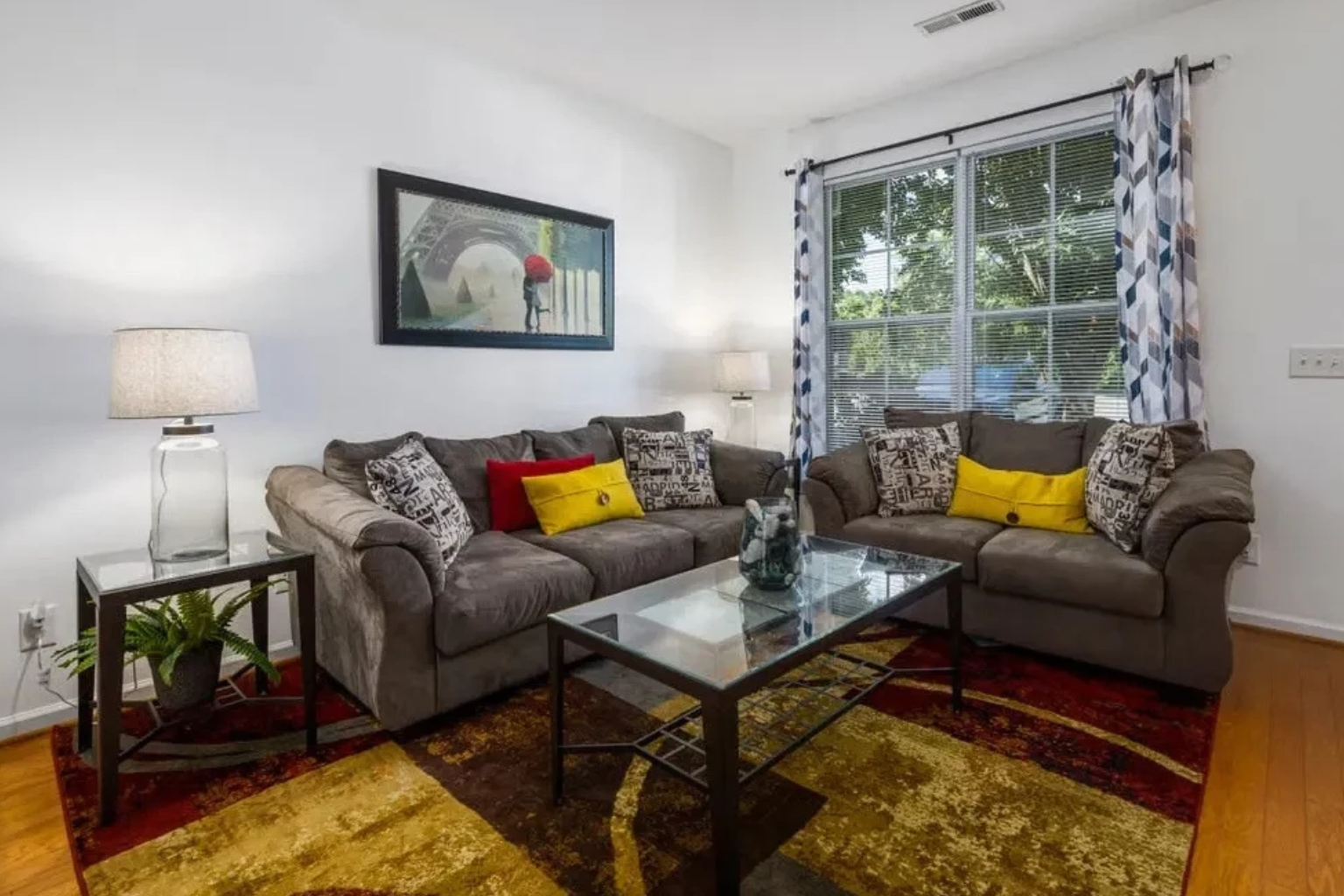 Living room before: busy red and gold rug, patterned curtains, mismatched pillows